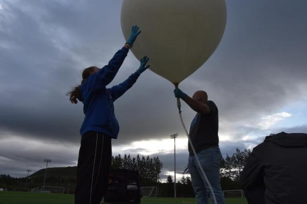 Two people holding a balloon.
